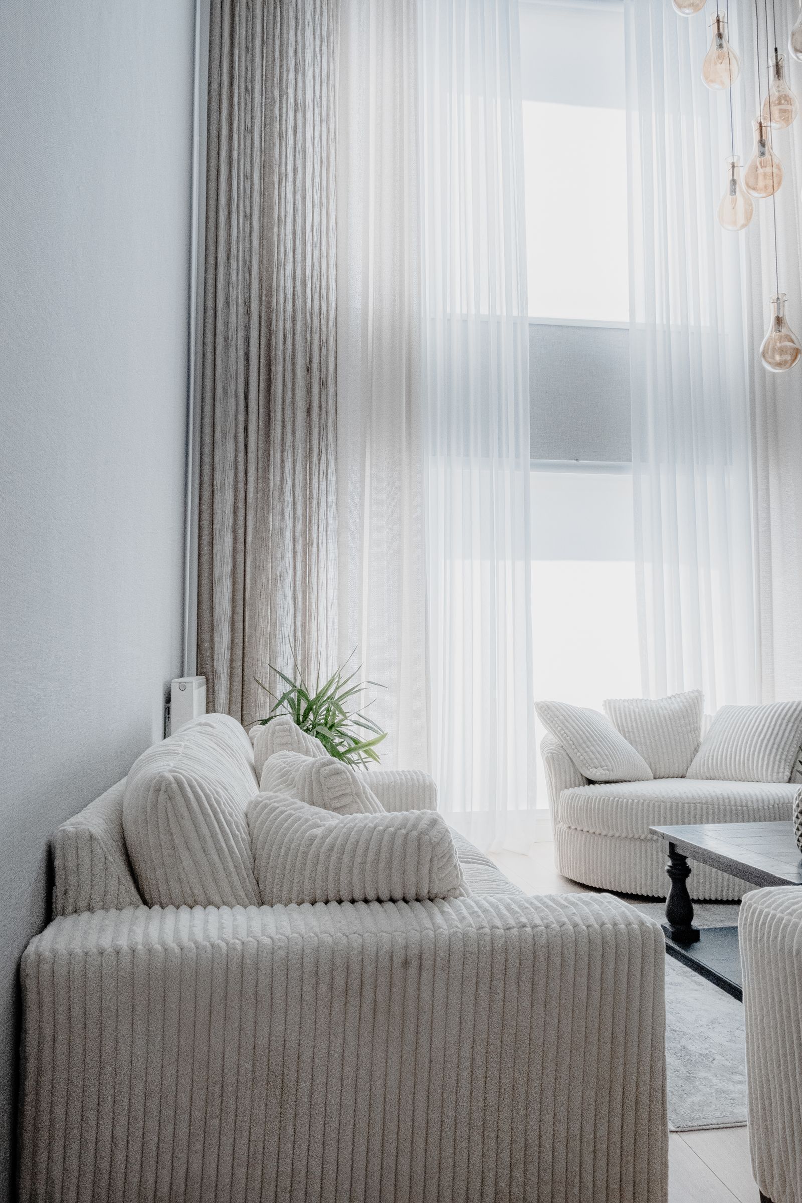 A double-height lounge with tall windows and sheer curtains.