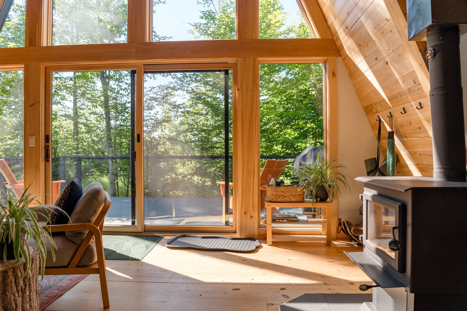 An A-frame living room with a glazed wall opening onto a green deck.