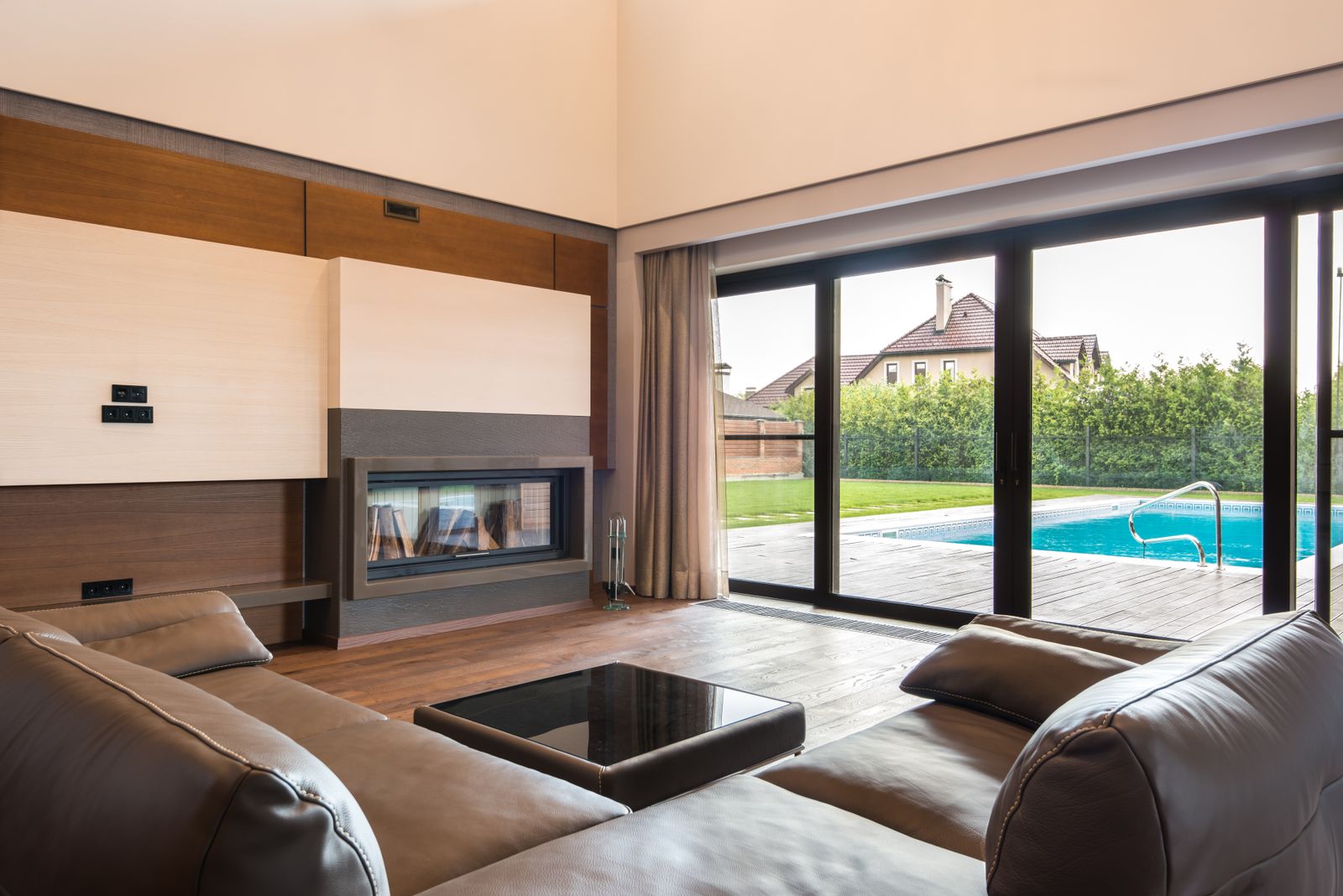 A living room with wide glass doors opening to a pool deck.