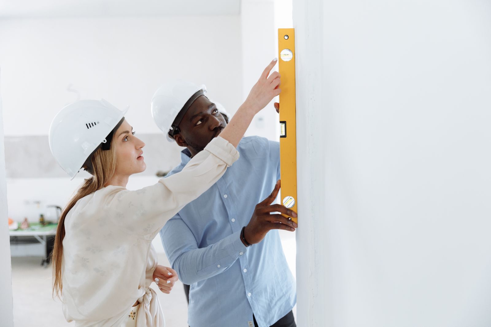 Two installers checking a wall with a spirit level during a renovation.
