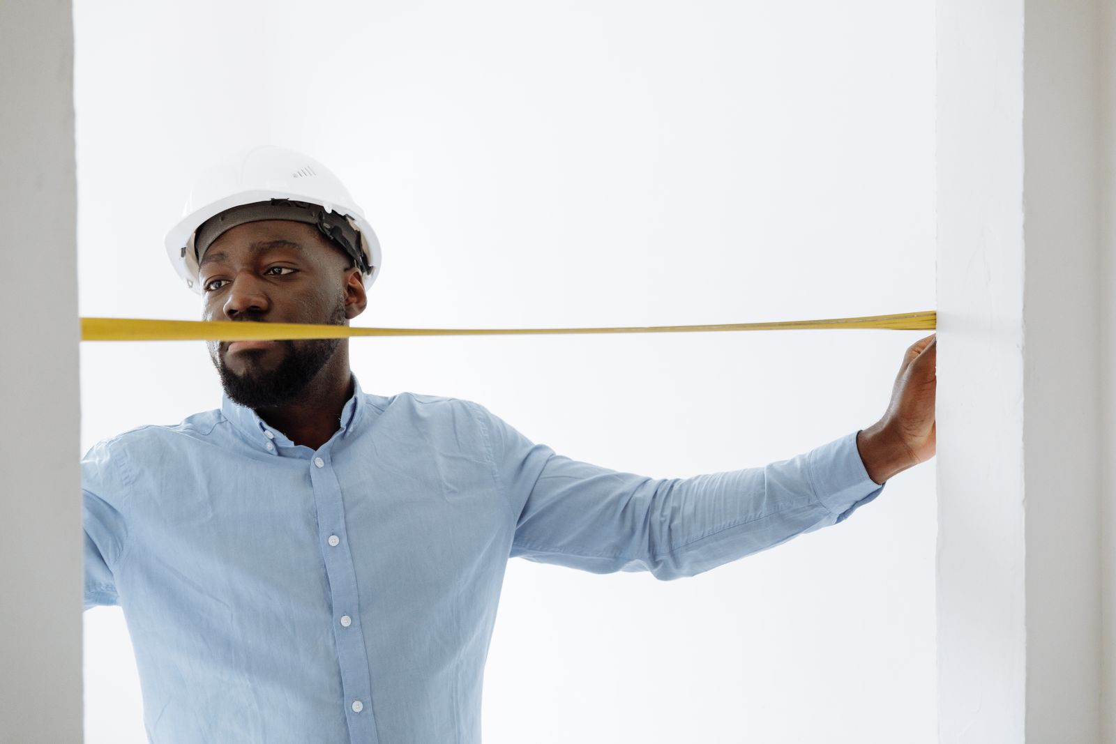 A technician checking the width of a window opening with a tape measure.
